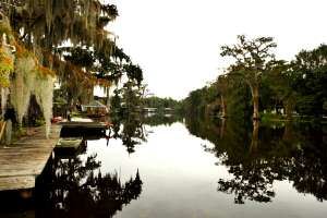A river lined with docks, houses, and trees in the bayou